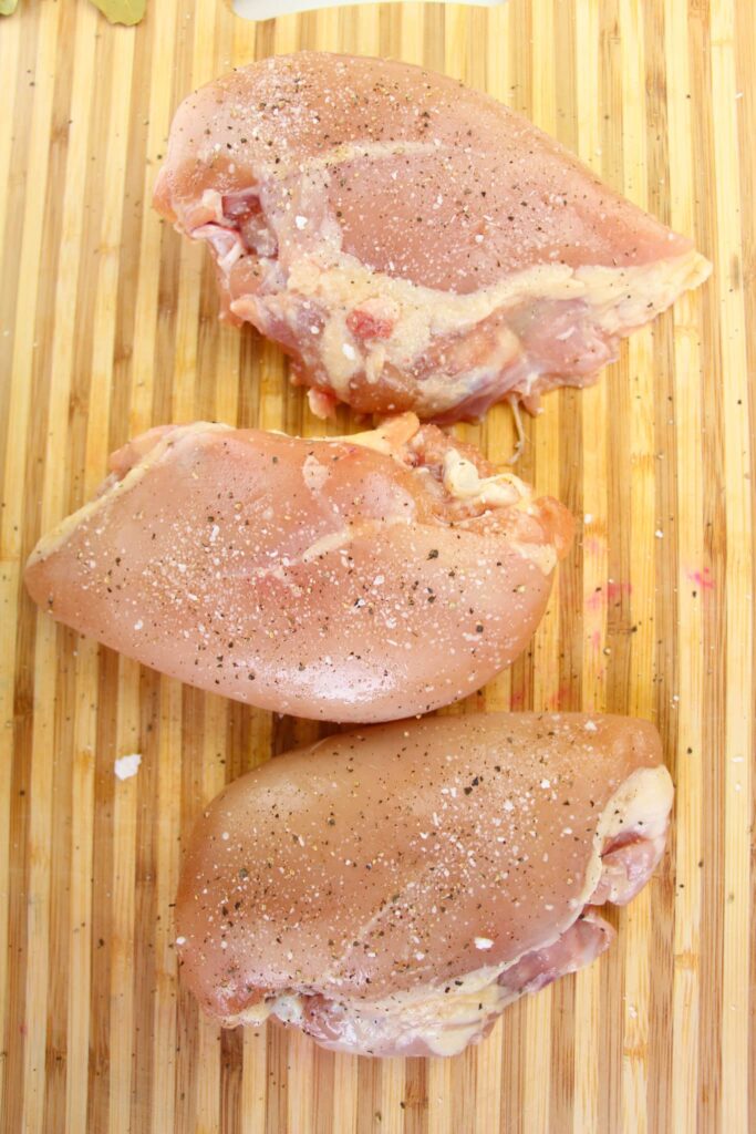 Seasoned chicken breasts on a wooden board.