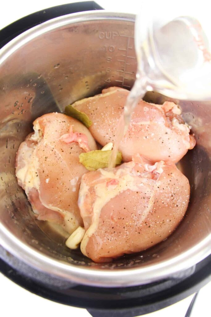 Pouring broth over chicken breasts.