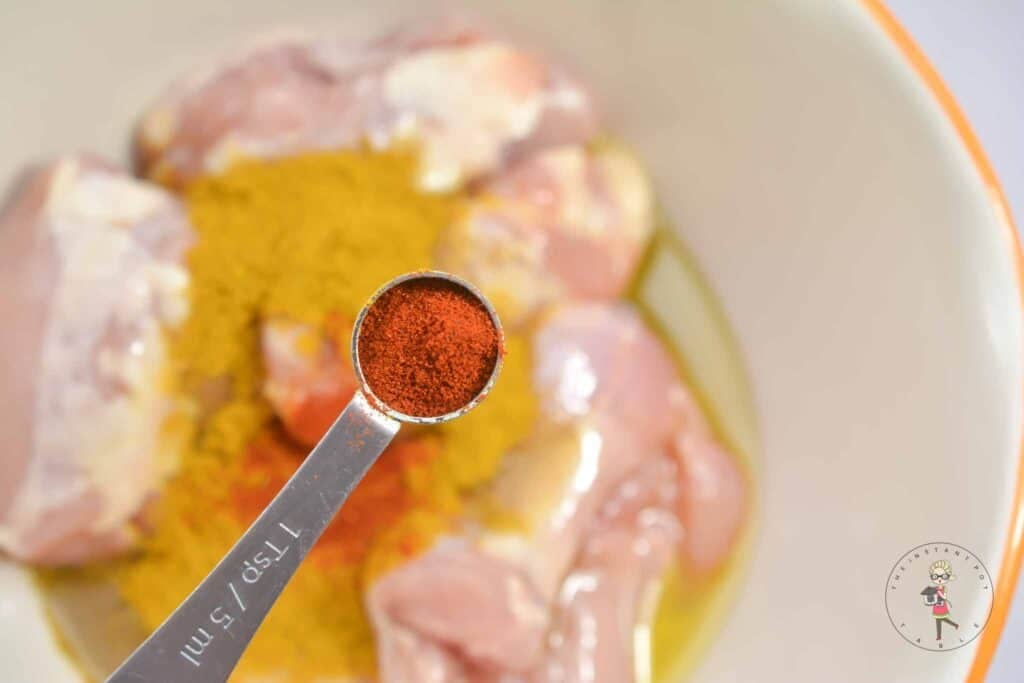 Adding paprika to raw chicken.