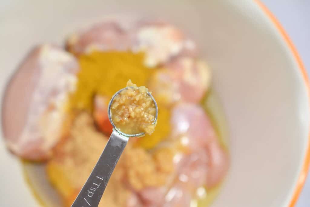Adding garlic to raw chicken.